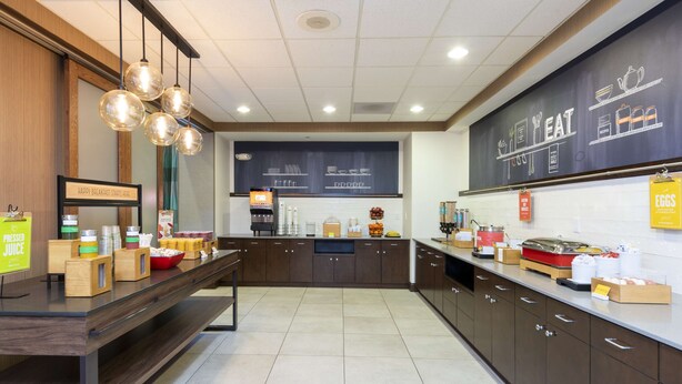 A modern kitchen with a breakfast bar, various food items, and a chalkboard menu. - Hampton Inn & Suites Fort Myers - Colonial Blvd (Fort Myers)
