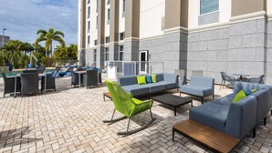 A rooftop patio with outdoor seating, a pool, and palm trees. - Hampton Inn & Suites Fort Myers - Colonial Blvd (Fort Myers)