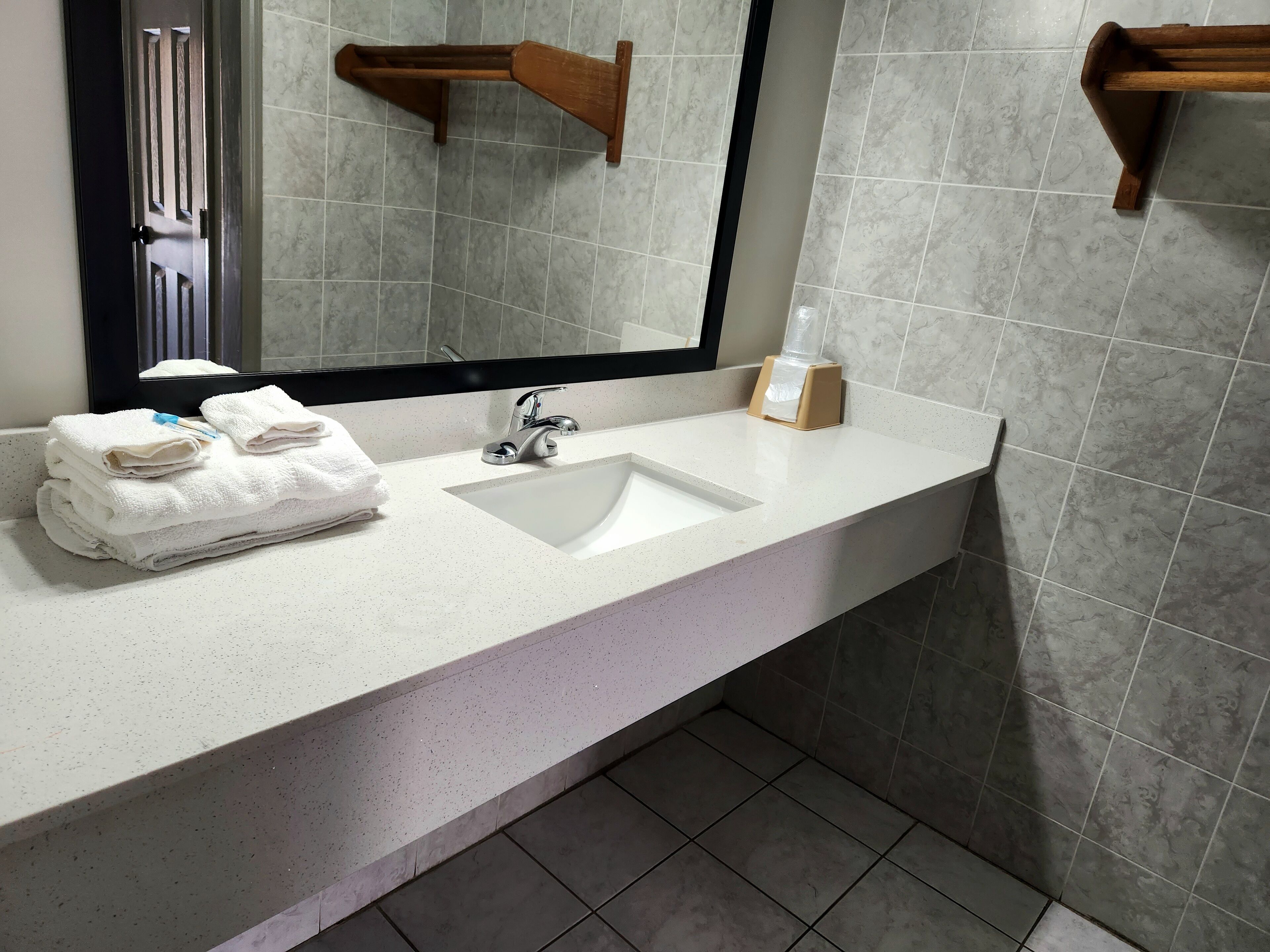 A bathroom with a white sink, a mirror, and a towel rack.