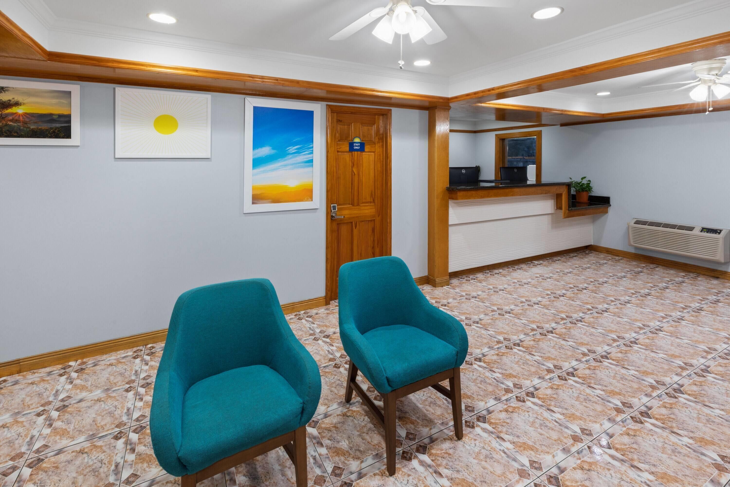 A reception area with two teal chairs, a wooden reception desk, a wall-mounted air conditioner, and a door with a sign.