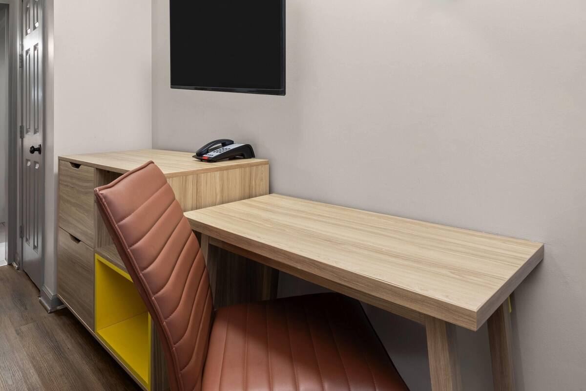 A corner desk with a telephone, a brown chair, and a yellow storage unit.