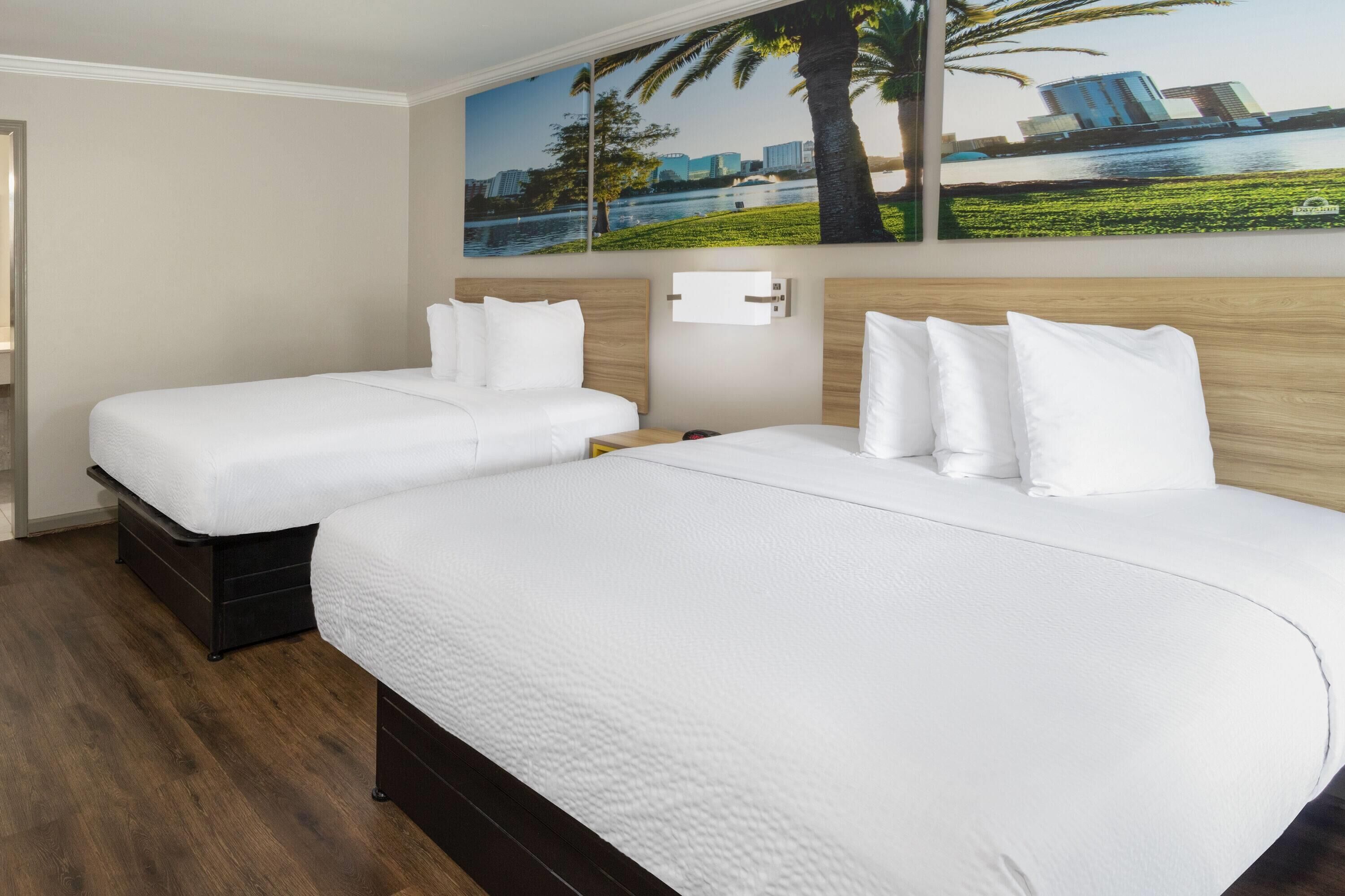 Habitación de hotel con dos camas, cabecero de madera, mesita de noche y lámpara fijada a la pared.