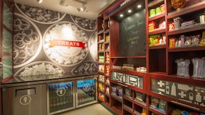 Una tienda de dulces con estantes llenos de diversas golosinas y un letrero que dice "TREATS".