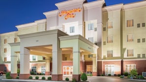Un hotel Hampton Inn con fachada moderna, múltiples entradas y una entrada bien iluminada.