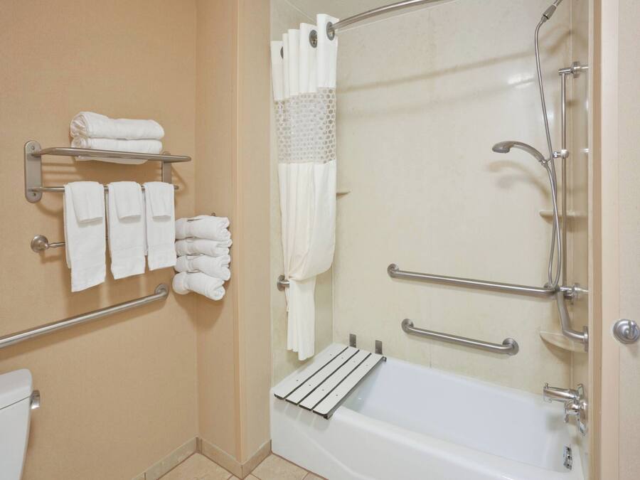 A bathroom with a bathtub, a shower with a glass door, and towel racks with neatly folded towels.