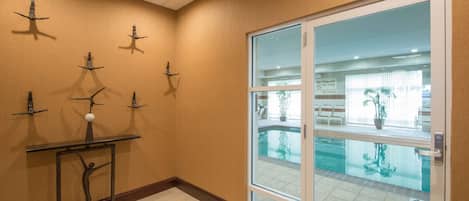A hotel lobby with a pool view, a reception desk, and a wall with decorative metal sculptures.