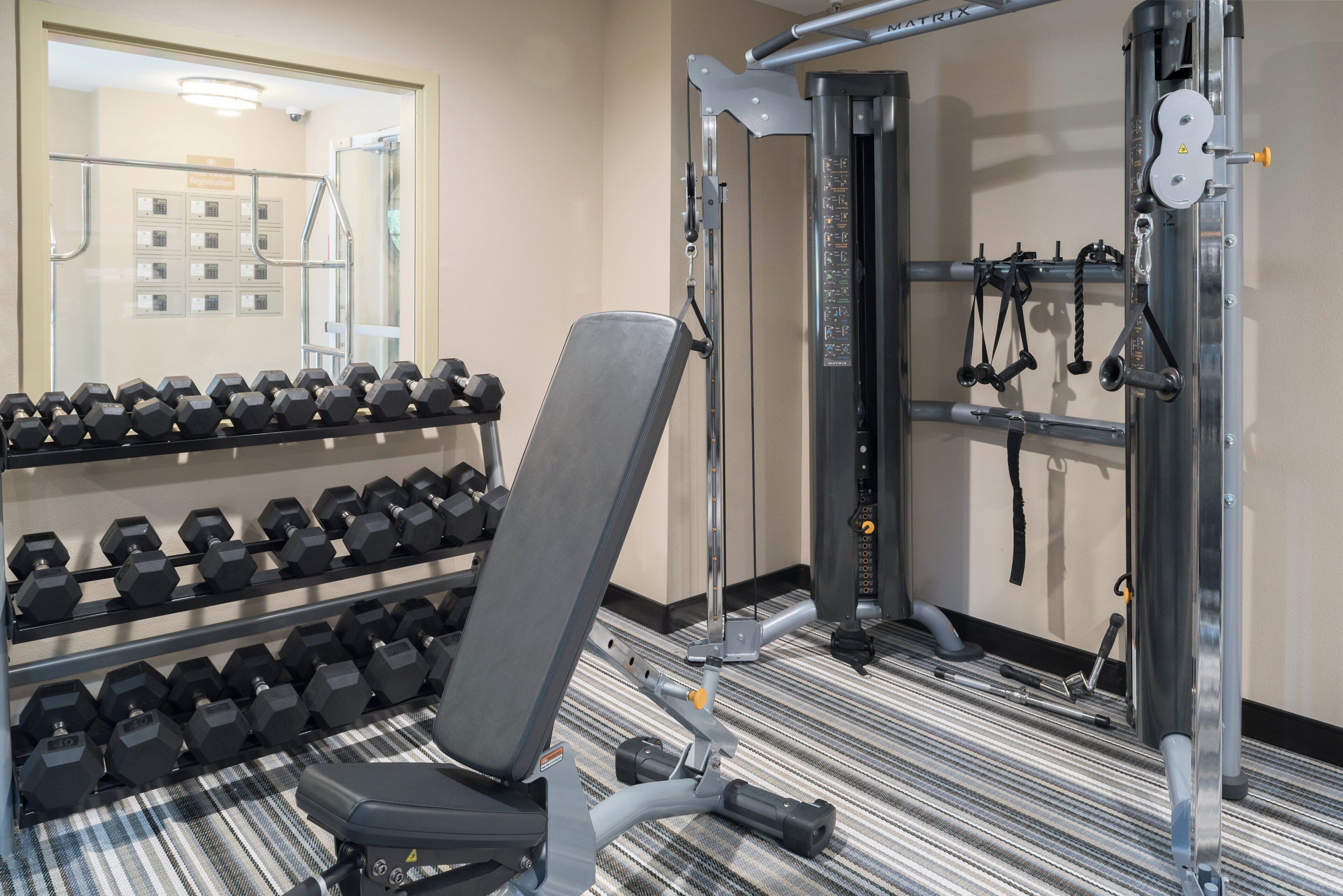 Ein Fitnessraum mit Krafttrainingsgeräten, einer Bank und einer Hantelbank.