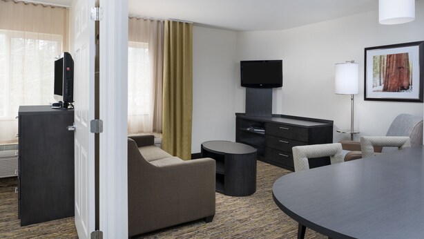Habitación de hotel con sofá, una mesa redonda, televisión, escritorio y lámpara.