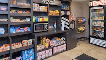 Un espacio de autoservicio con diferentes opciones de bocadillos, microondas y dispensador de bebidas.