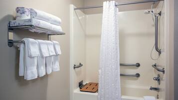 A bathroom with a shower, a bathtub, and a towel rack with folded towels.