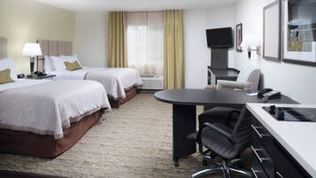 A hotel room with two beds, a desk with a chair, a television, and a phone.