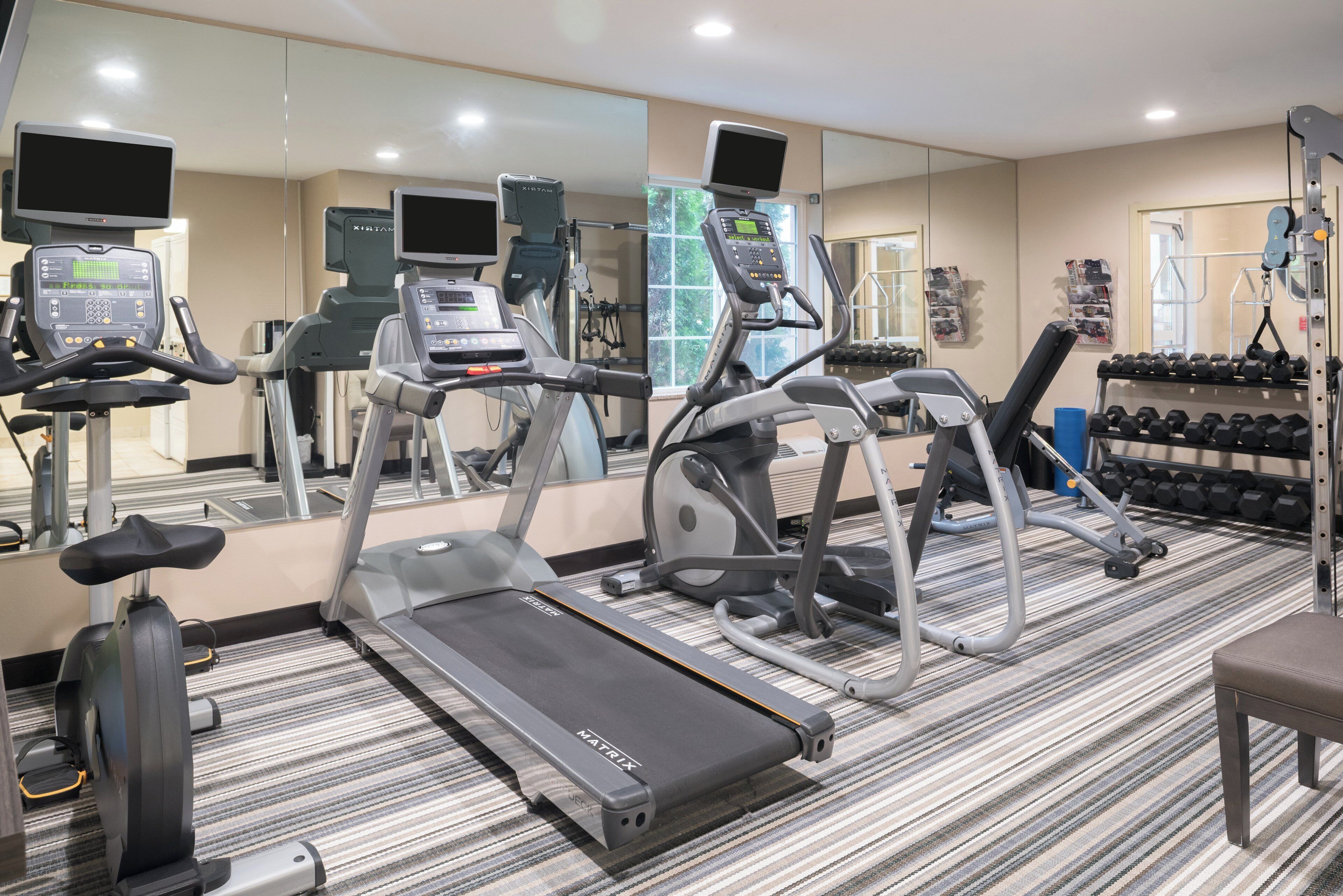 Un gimnasio con cintas de correr, elípticas y pesas libres.