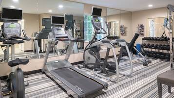 A gym with treadmills, elliptical machines, and free weights.