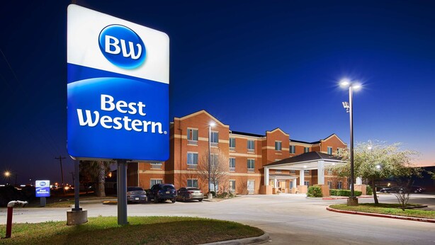 Un hôtel Best Western, reconnaissable à son grand panneau, à ses bâtiments en briques et à son parking.