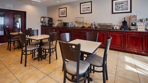 Un espace de restauration dans l’hôtel, comprenant des tables et des chaises, un coin café et une cuisine.