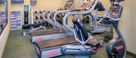 A gym with treadmills, elliptical machines, and dumbbells.