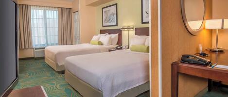 A hotel room with two beds, a desk with a telephone, and a television.