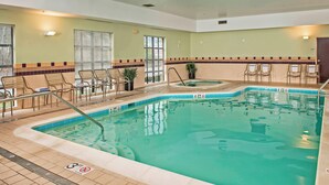Une piscine intérieure à l’eau claire, avec un sol carrelé et quelques chaises longues.