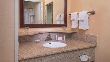 A bathroom with a granite countertop, a sink, a mirror, and a towel rack with towels.