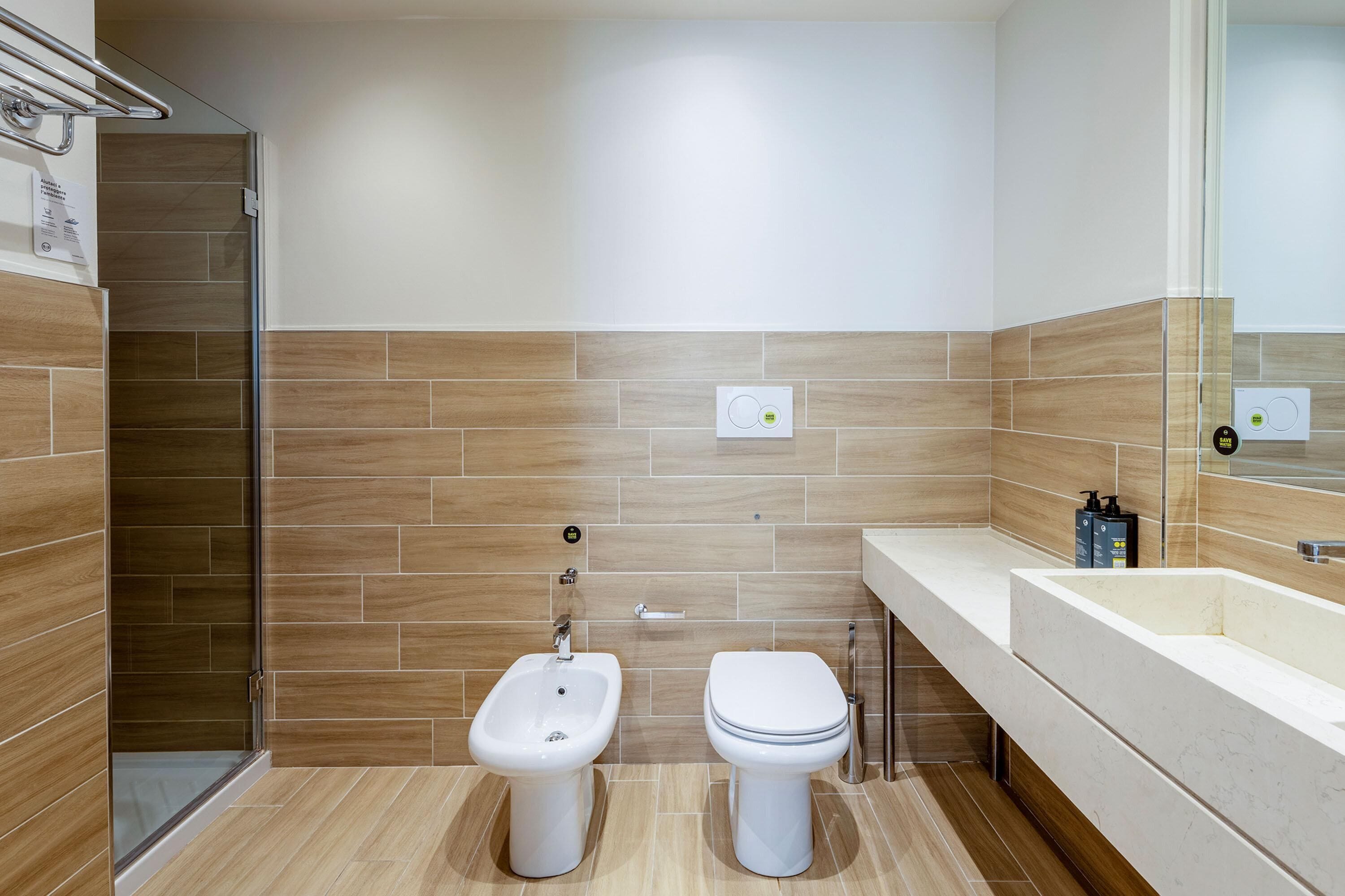 A modern bathroom with a bidet, toilet, and a glass shower enclosure.
