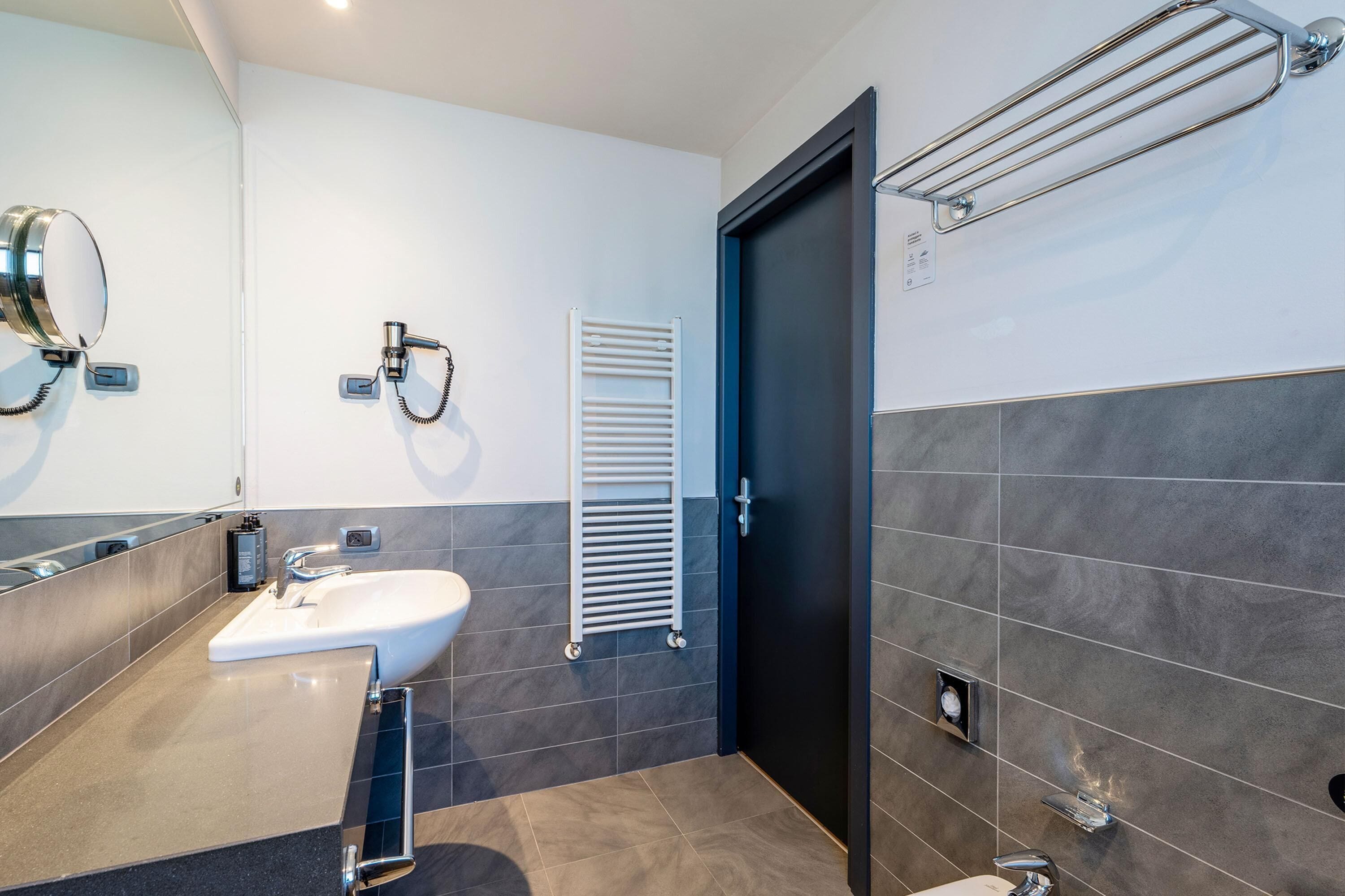 Un baño moderno con lavabo, espejo, toallero y una puerta.