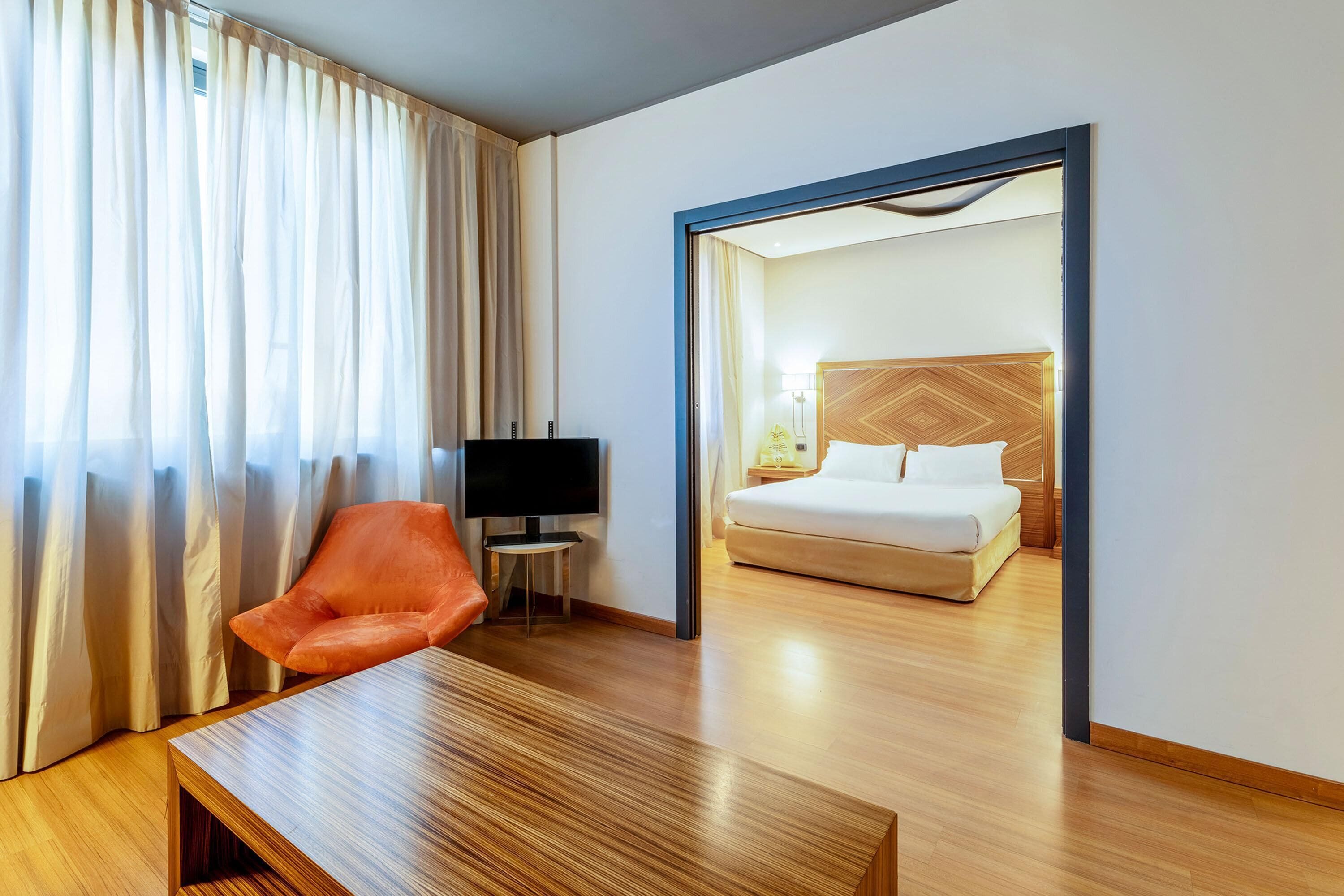 Habitación de hotel con cama, televisión, una mesa de madera y una silla.