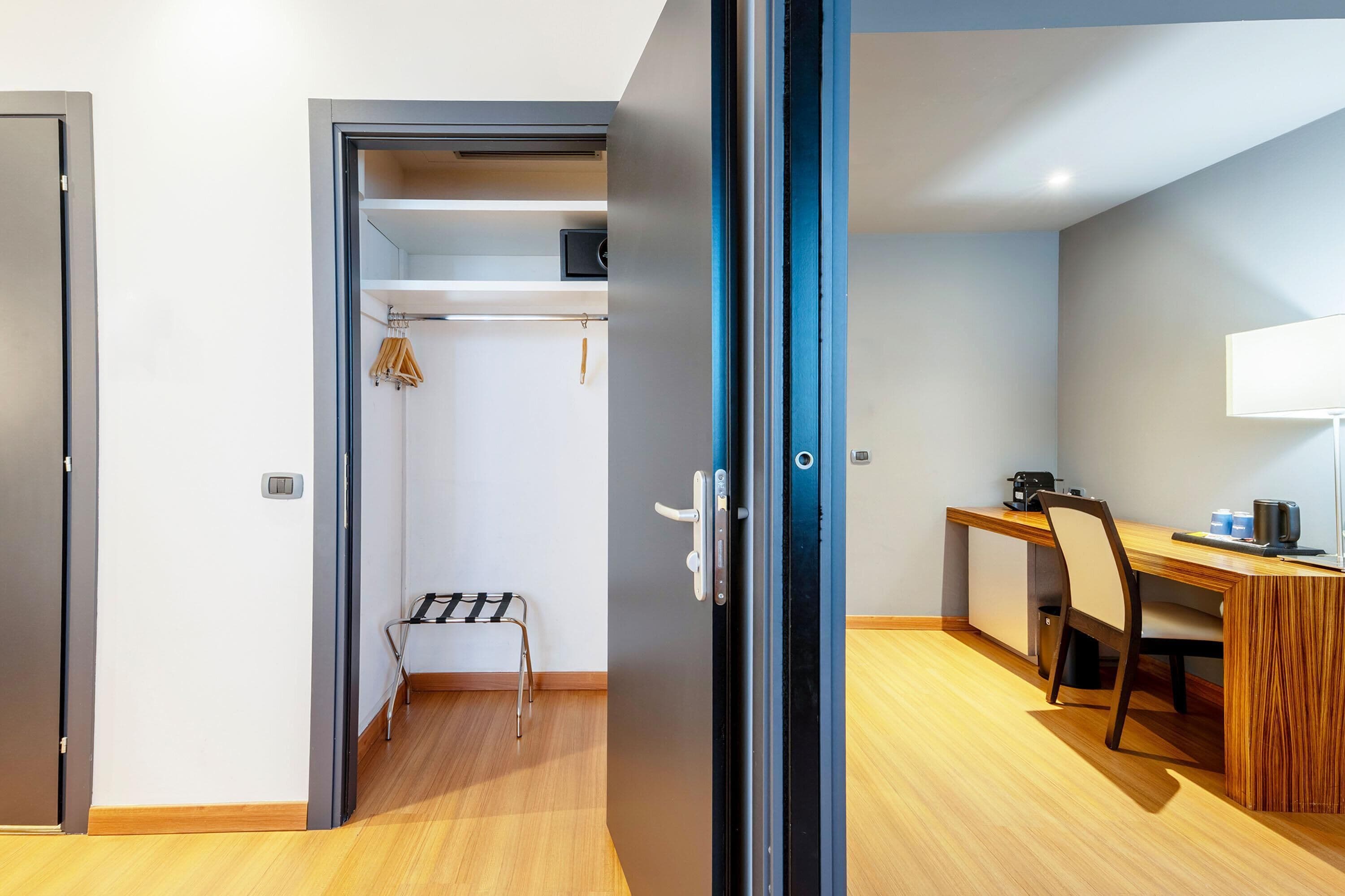 Een kamer met een houten bureau, een stoel, een lamp en een klein kitchenette.