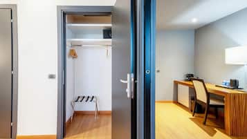Een kamer met een houten bureau, een stoel, een lamp en een klein kitchenette.