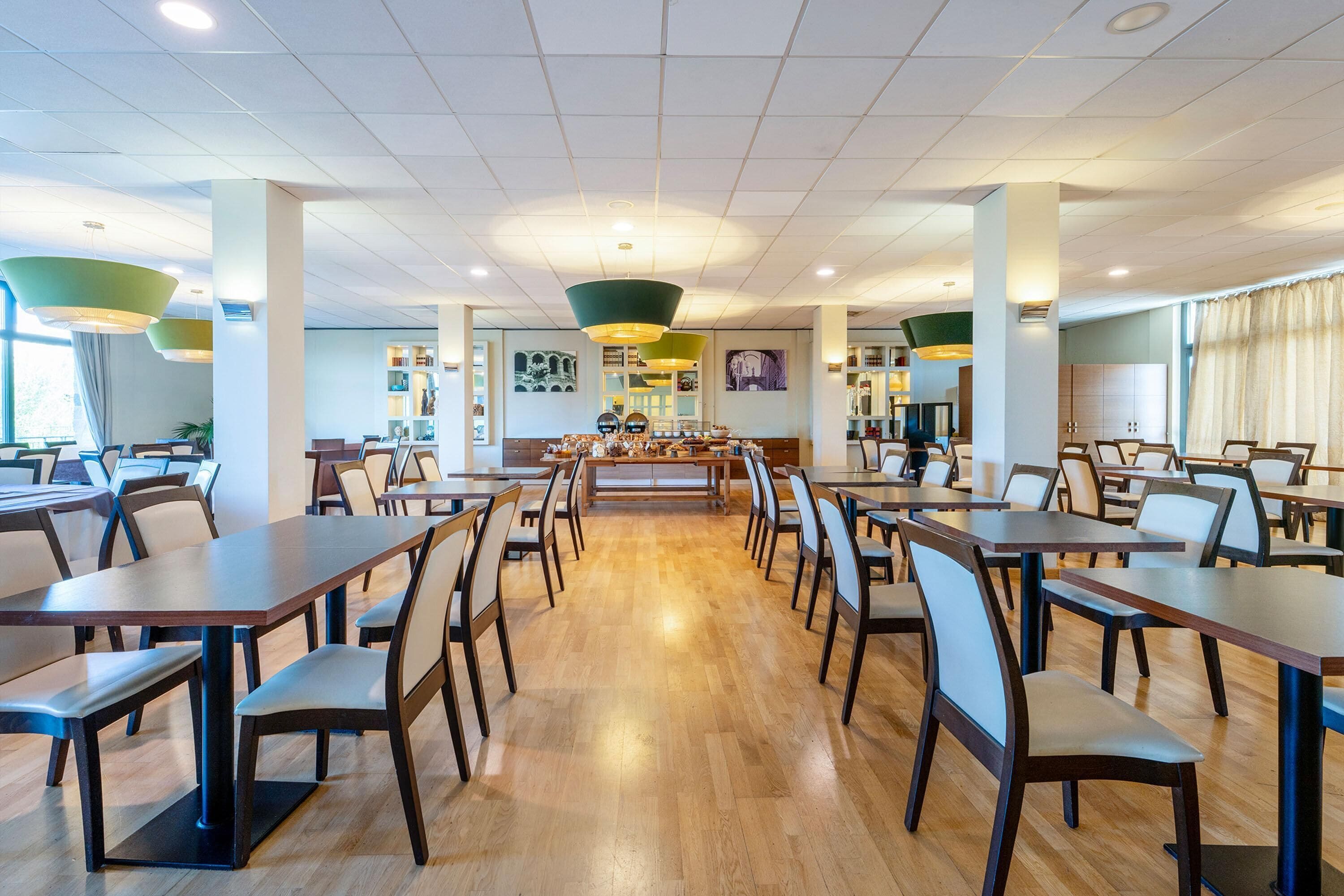 A spacious dining area with multiple tables and chairs, a central counter, and artwork on the walls.