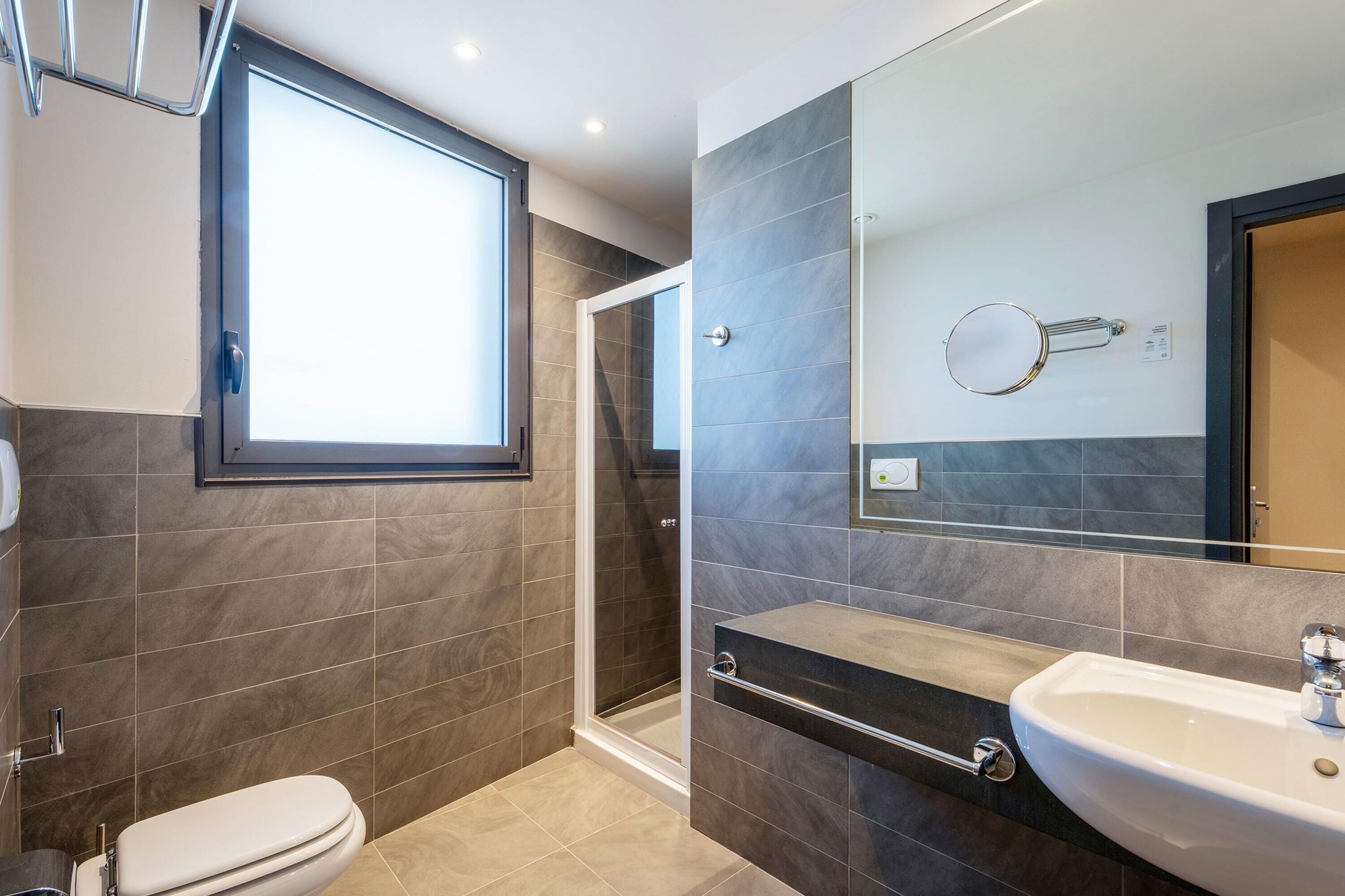A modern bathroom with a toilet, shower, and sink.