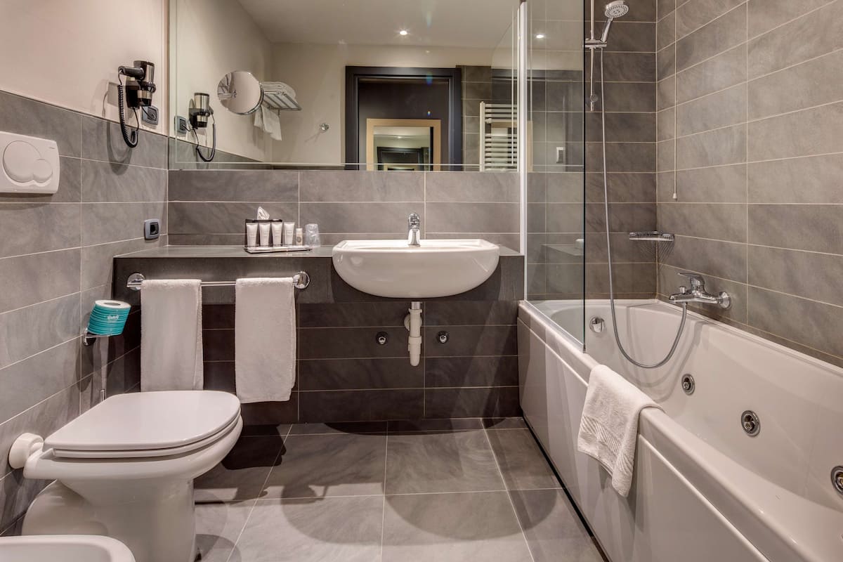 deluxe room, 1 queen bed, non smoking, jetted tub | bathroom | combined shower/bathtub, eco-friendly toiletries, hair dryer, slippers