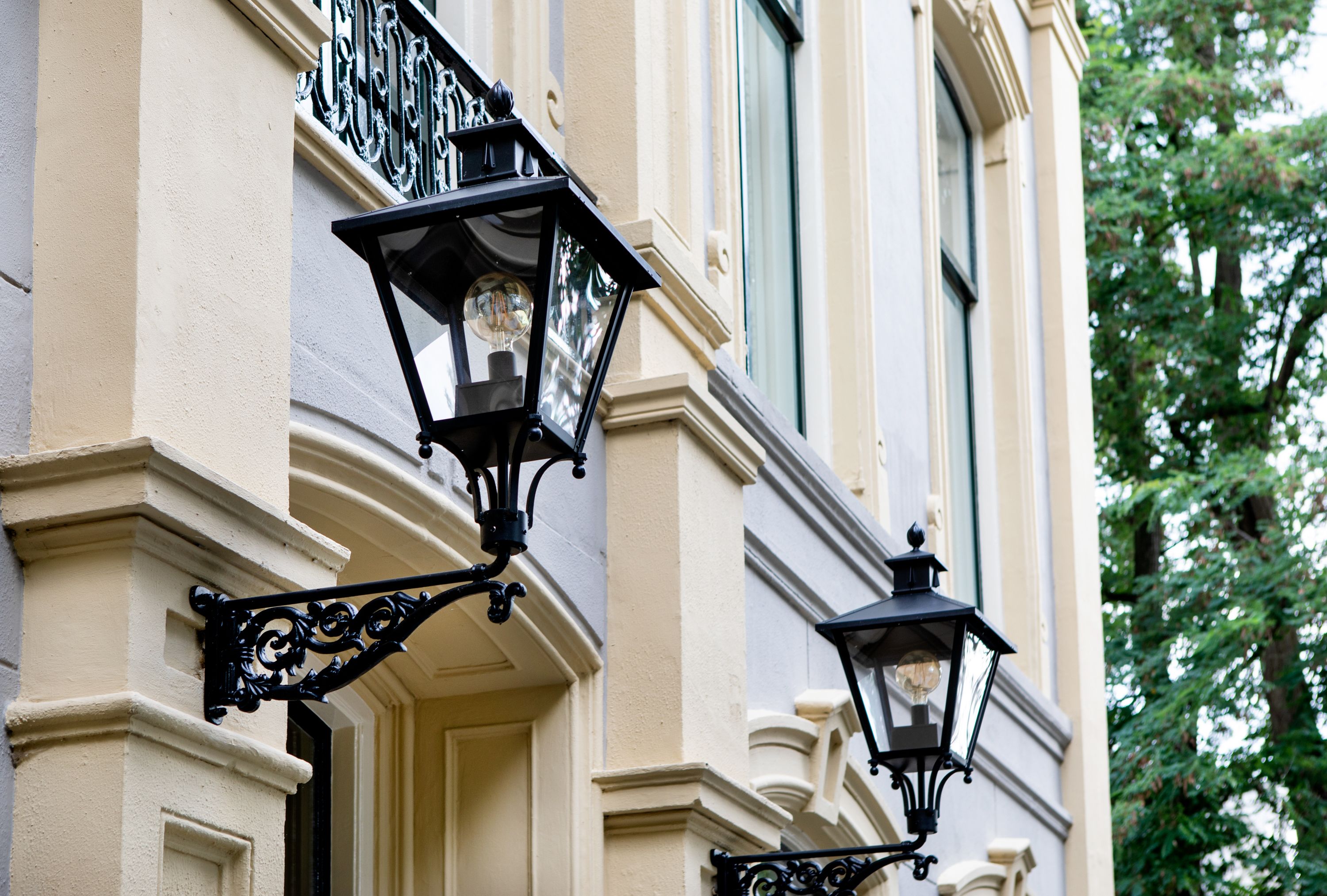 Facciata di un edificio in stile classico, con elaborate lampioni in metallo nero.