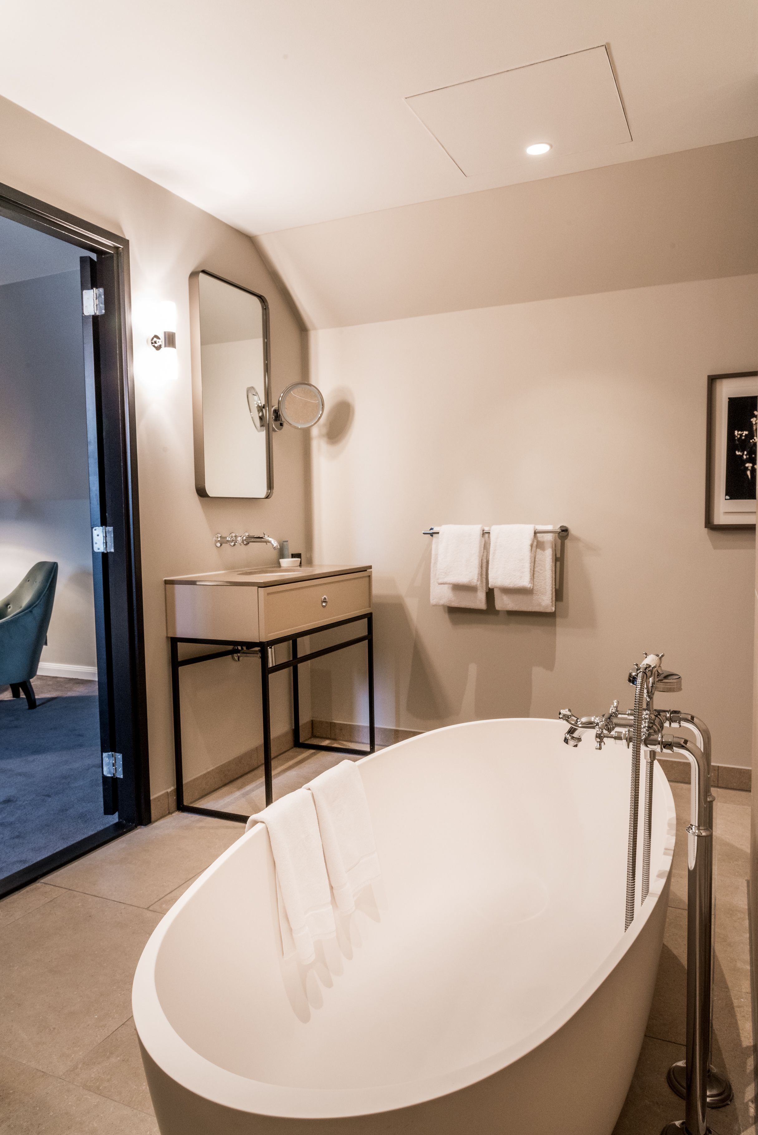 A modern bathroom with a freestanding bathtub, a vanity with a mirror, and a towel rack.