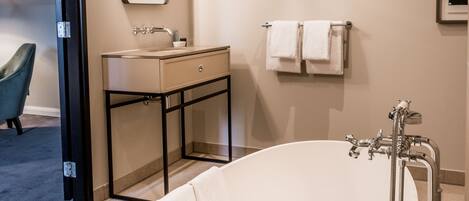 A modern bathroom with a freestanding bathtub, a vanity with a mirror, and a towel rack.