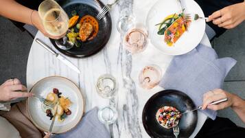 A round table with four plates of food, each accompanied by a fork and a glass of water.