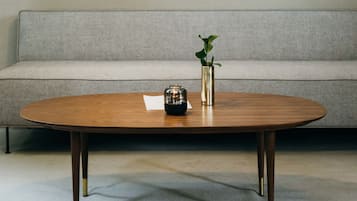 A modern living room with a wooden coffee table, a grey sofa, and six framed pictures on the wall.