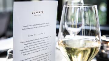 A menu titled "COPERTO RESTOBAR" with a glass of white wine.