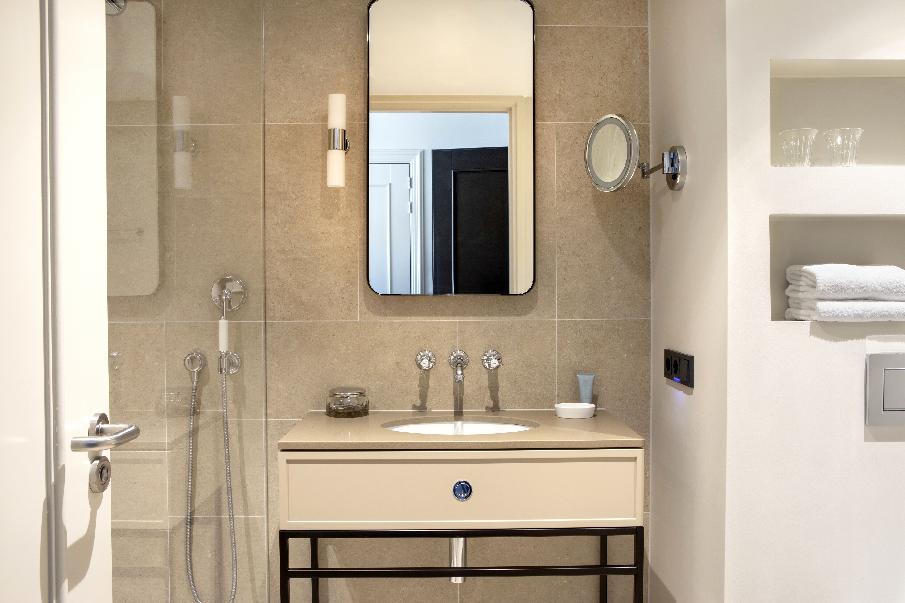 A modern bathroom with a sink, mirror, and shower.
