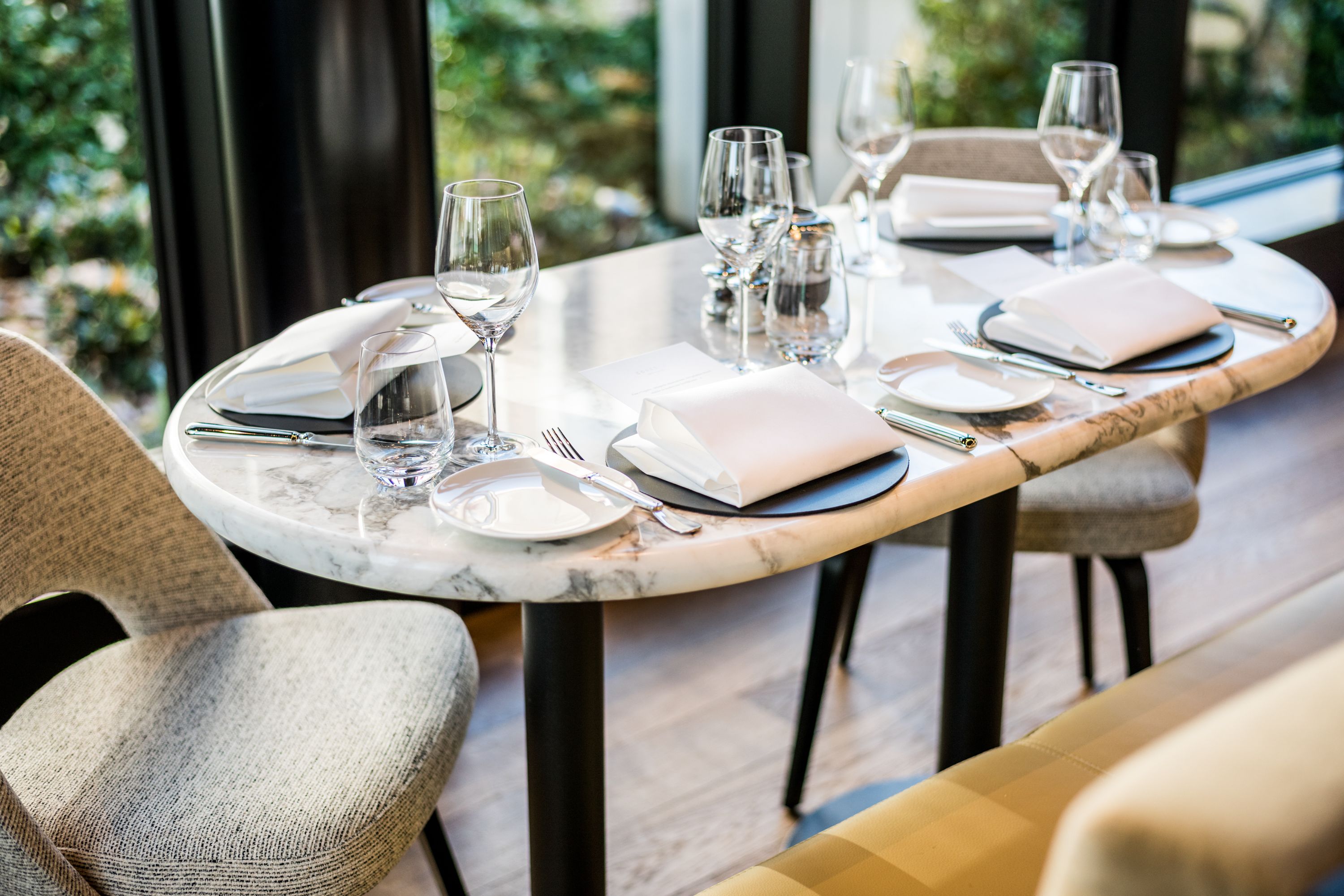 Mesa de jantar para quatro pessoas, com tampo de mármore, rodeada por cadeiras estofadas.