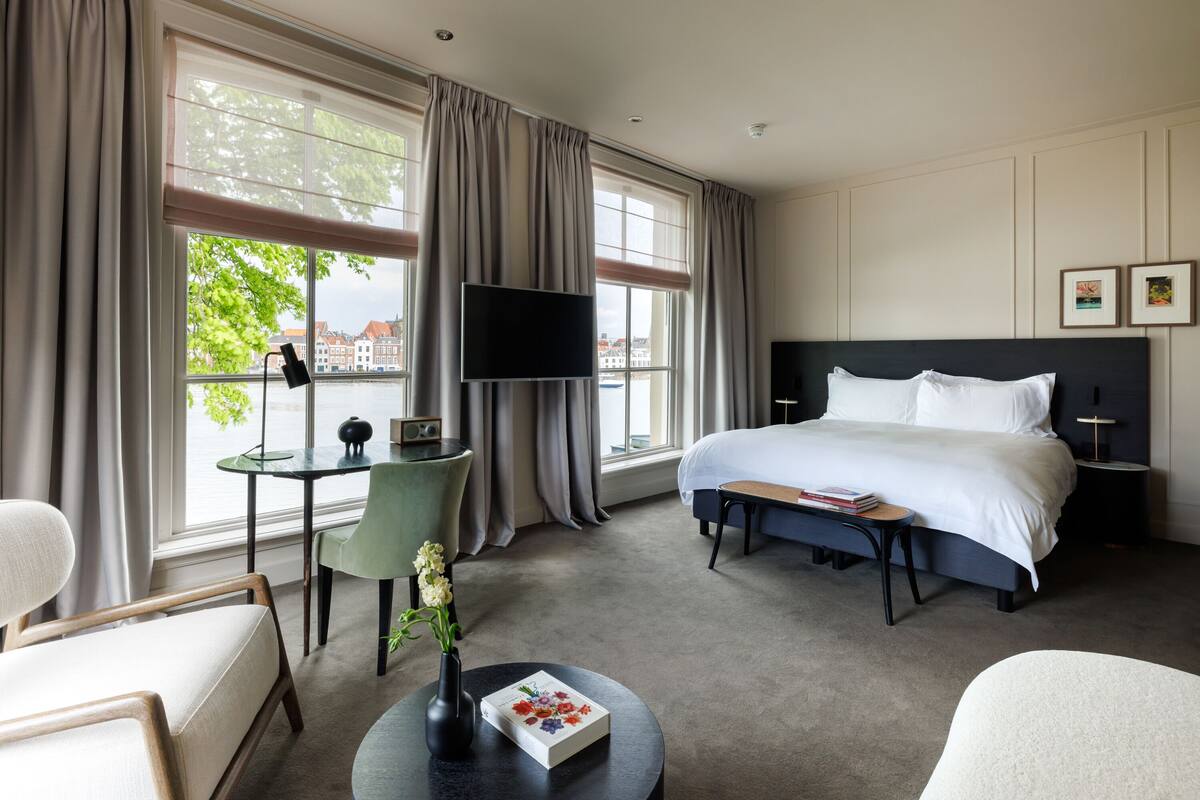 Una habitación de hotel con una cama grande, un escritorio con una silla, un televisor y vistas a la ciudad.