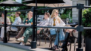 An outdoor dining area with tables and chairs, umbrellas, and a railing. - Pillows Luxury Boutique Hotel Aan De IJssel (Deventer)