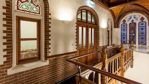 A staircase with wooden railings and stained glass windows. - Fletcher Hotel Gilde (Deventer)