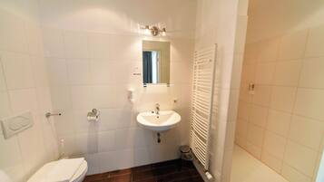 Ein Badezimmer mit einem weißen Waschbecken, einem Spiegel, einer Toilette und einer Duschkabine.