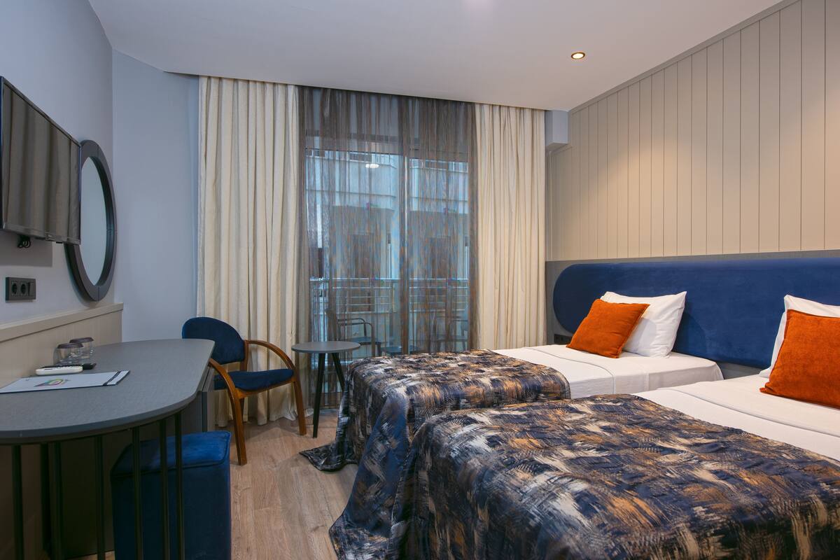 A hotel room with two beds, a desk, and a chair.