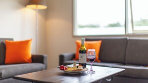 A dining table with a bottle of wine, a glass, and a plate of cheese and crackers. - Harrigan's Hunter Valley (Pokolbin)