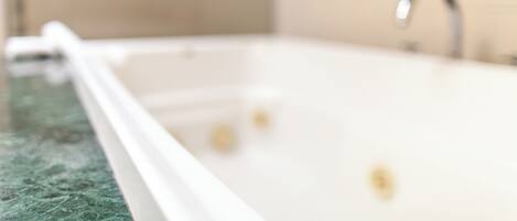 A bathroom with a bathtub, a sink, and a mirror.
