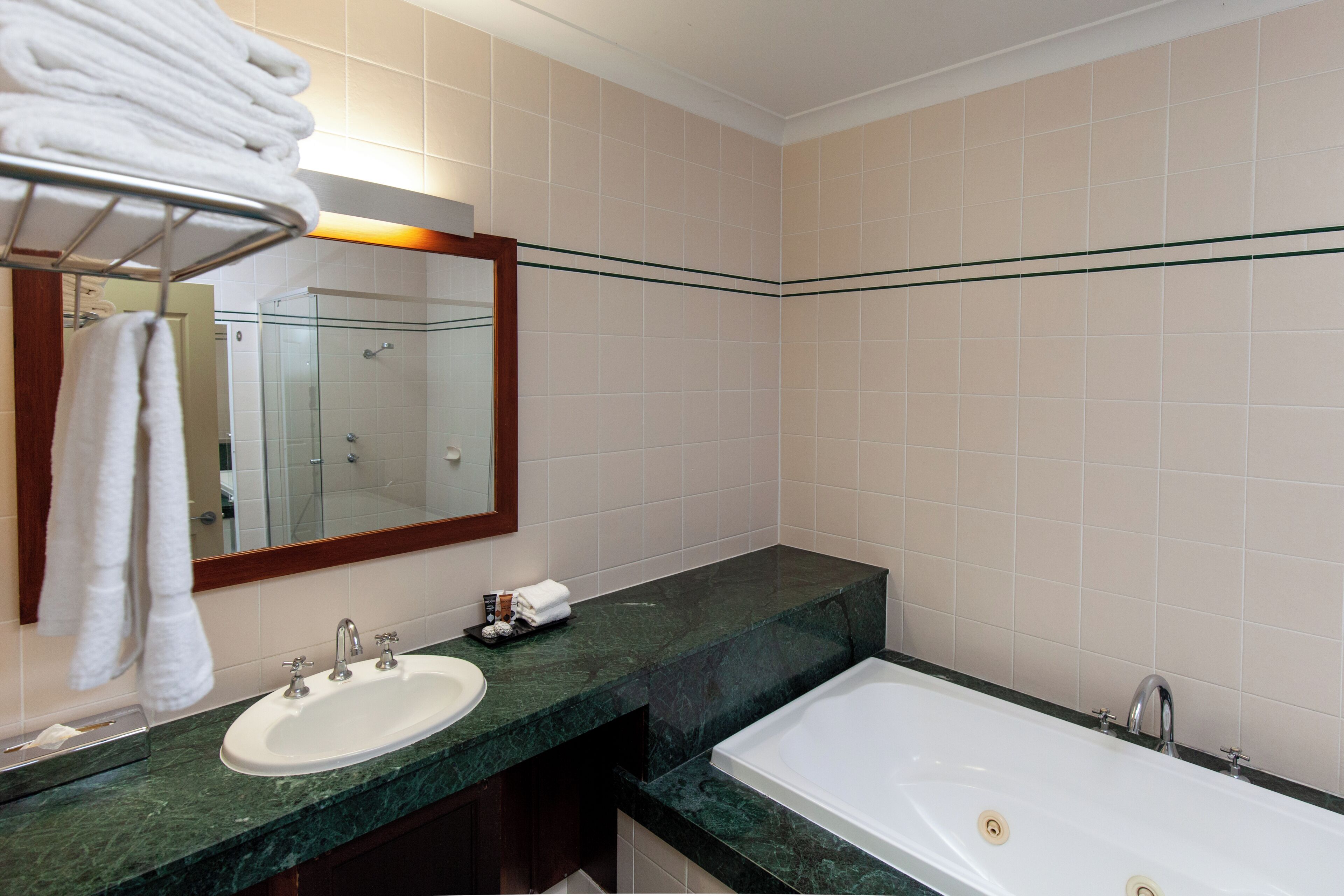 A bathroom with a sink, mirror, and bathtub.