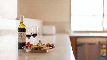 Una encimera de cocina con una botella de vino, una copa de vino tinto y un plato de comida.