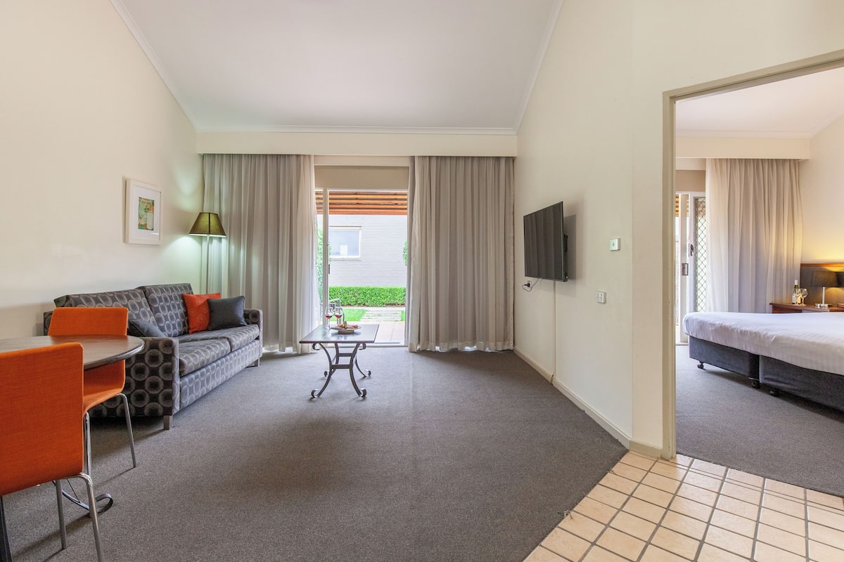 A hotel room with a sofa, a table, a TV, and a bed.