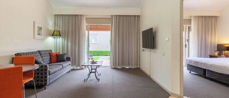 A hotel room with a sofa, a table, a TV, and a bed.